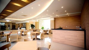 Un moderno vestíbulo de hotel con mostrador de recepción de madera, zona de estar y amplios ventanales.