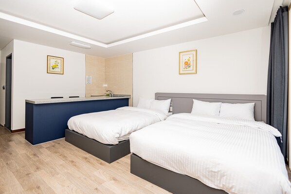 Habitación de hotel moderna con dos camas, un escritorio empotrado y un ventanal grande.