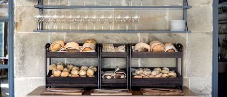 Eine Bäckereiauslage mit Brot, Gebäck und Weingläsern auf Regalen.