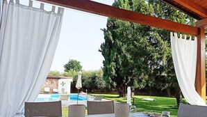 An outdoor dining area with a view of a swimming pool and a garden. - Il Giardino dei Pini (Capaccio-Paestum)