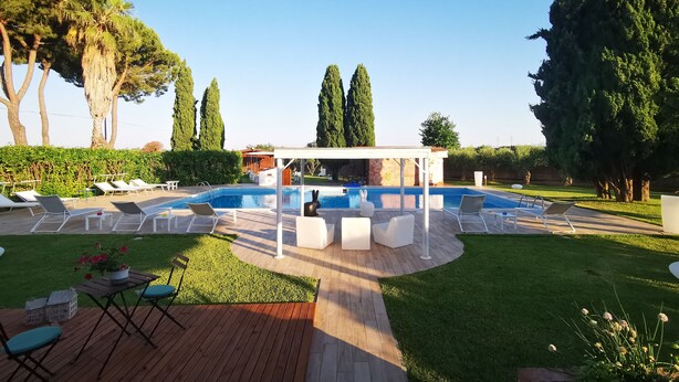 A pool area with lounge chairs, a covered seating area, and a well-maintained lawn. - Il Giardino dei Pini (Capaccio-Paestum)