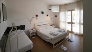 A hotel room with a single bed, bedside table, lamp, and a window with curtains. - Il Giardino dei Pini (Capaccio-Paestum)