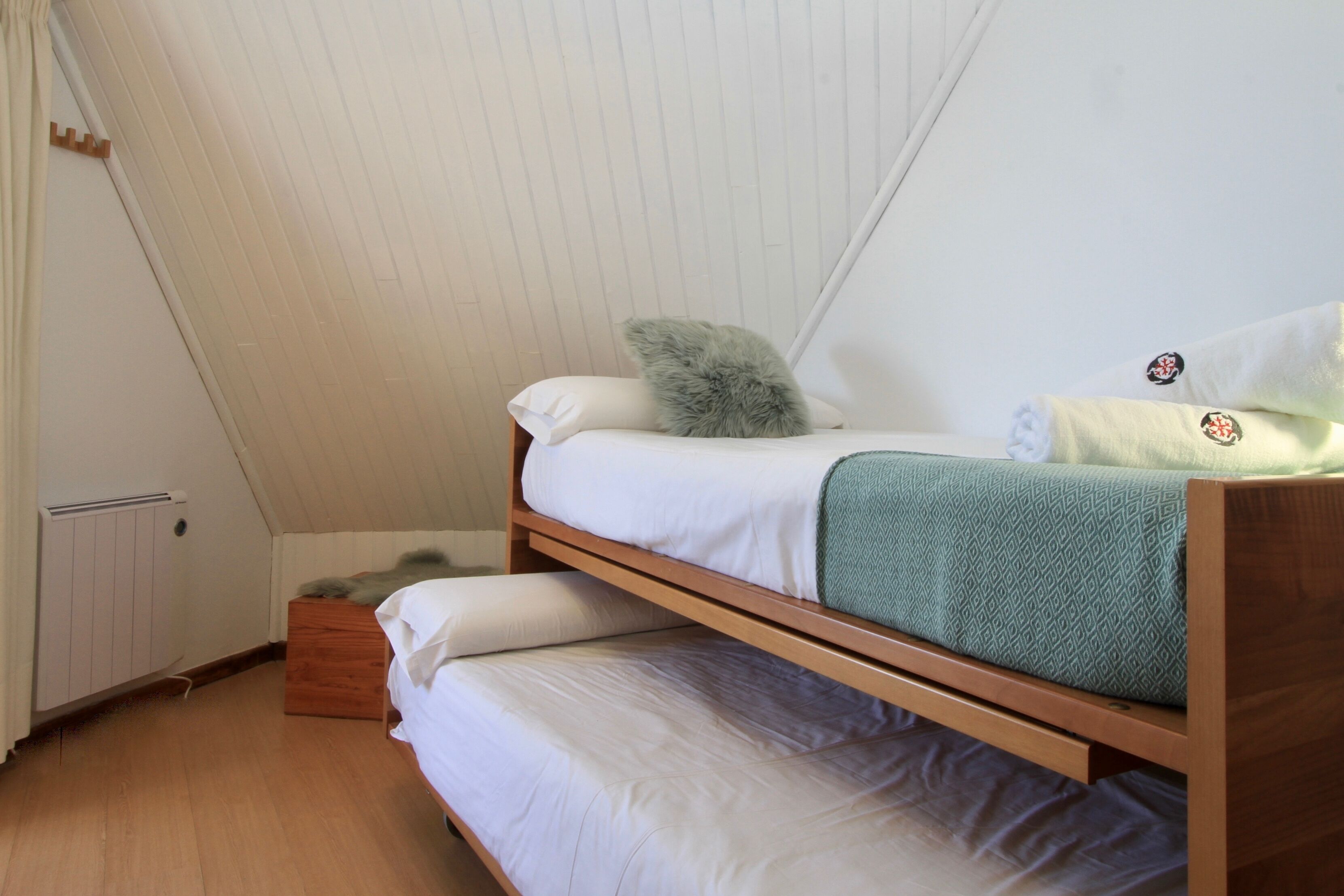 Una habitación con literas, un radiador y piso de madera.