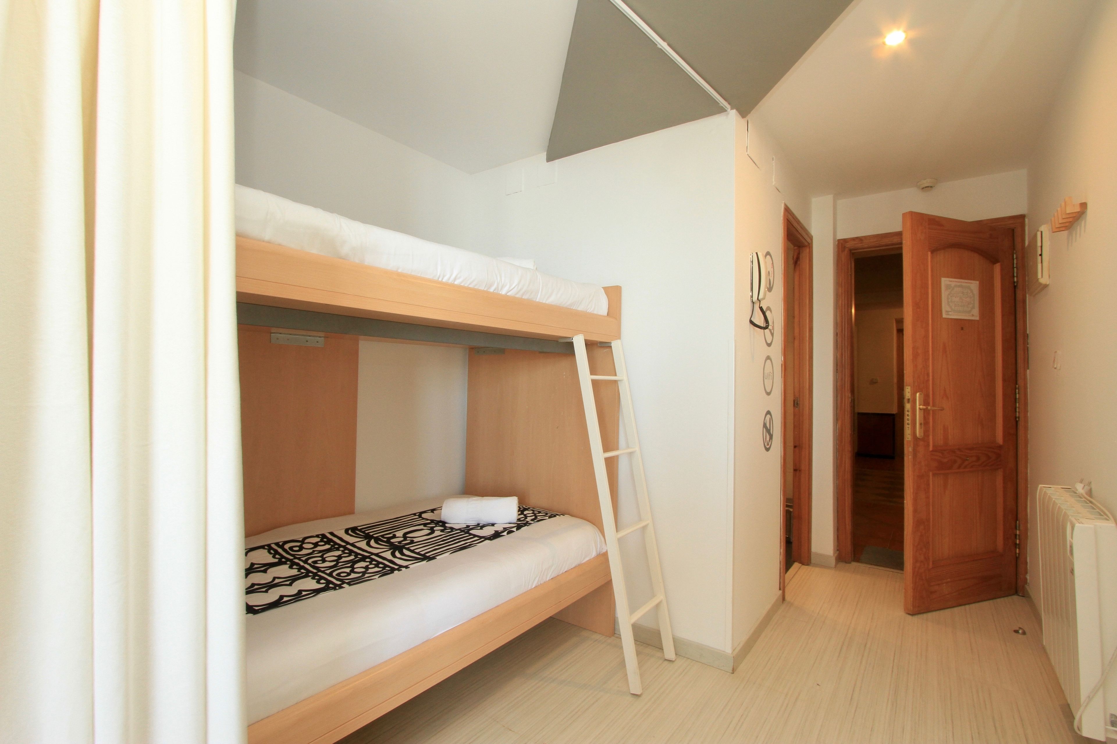 Habitación con literas, una escalera, una puerta y un radiador.