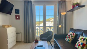 A modern living room with a sofa, a coffee table, a TV mounted on the wall, and a window with a view of a mountainous landscape. - Inside Plaza Sierra Nevada (Monachil)