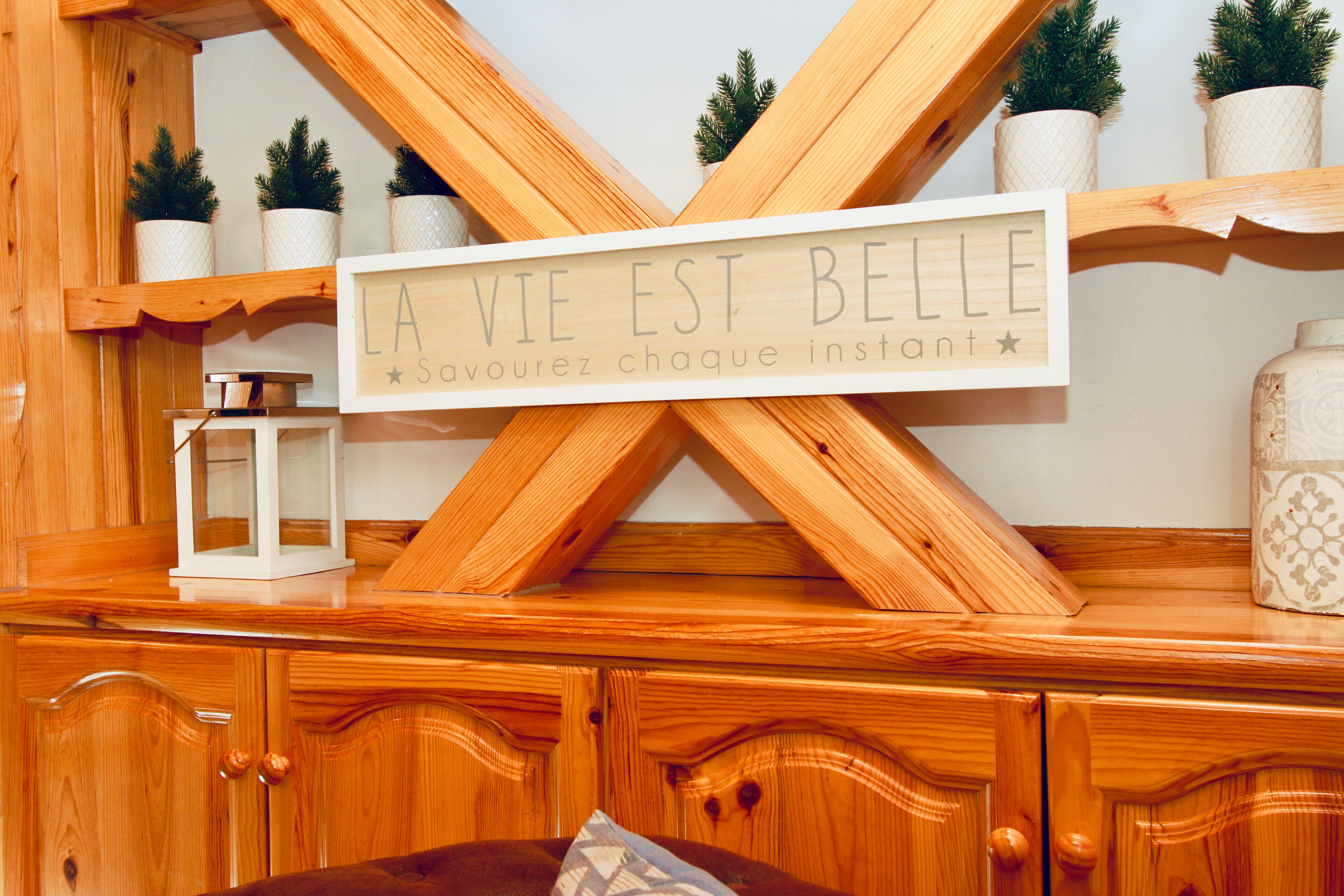 A wooden cabinet with a sign that reads "LA VIE EST BELLE" and a small white lantern.