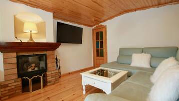 A cozy living room with a fireplace, a television mounted on the wall, and a comfortable sofa.