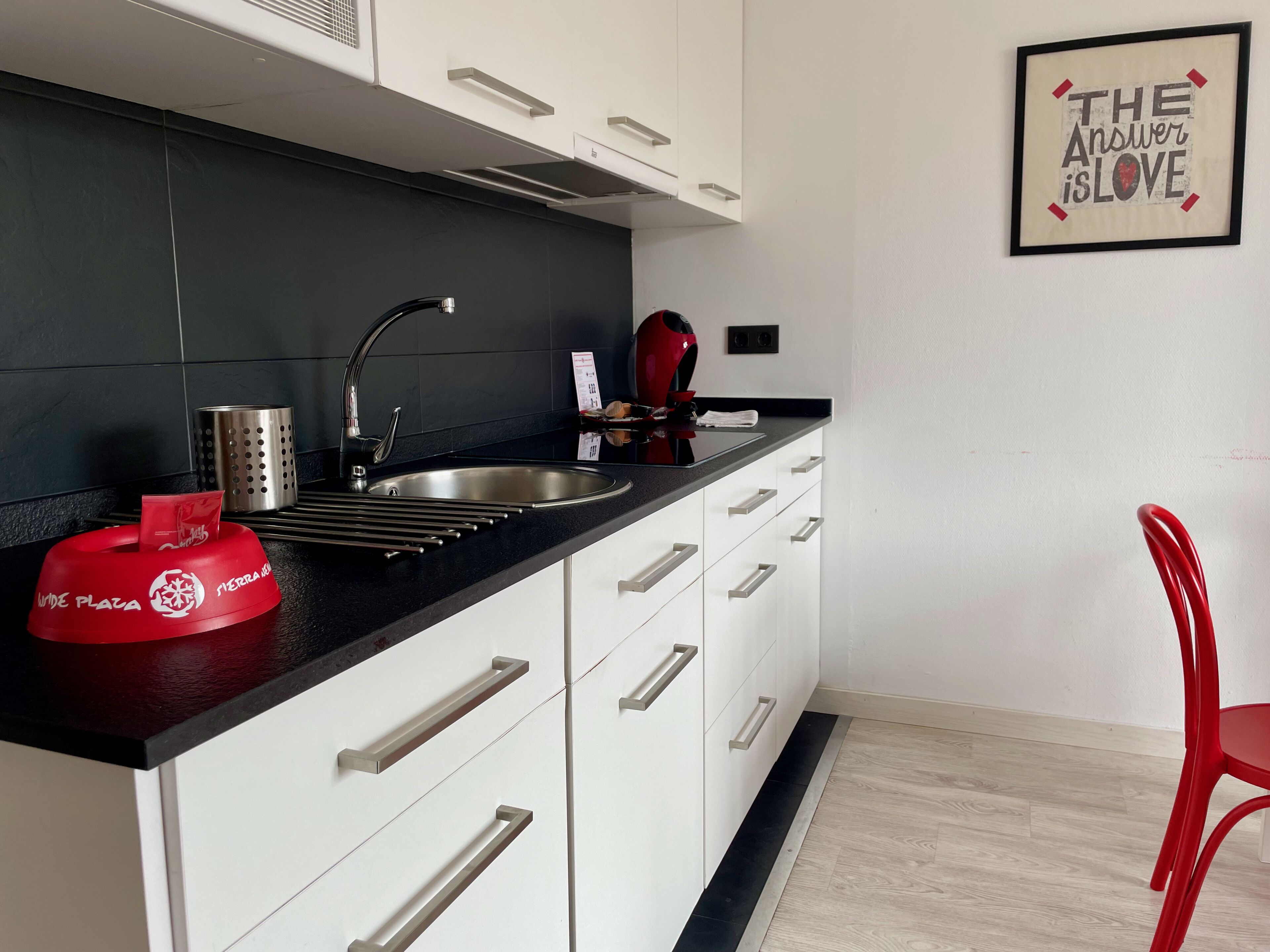 A modern kitchen with a black countertop, stainless steel sink, and white cabinets.