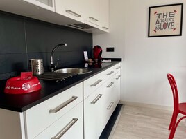 Una cocina moderna con encimera negra, pileta de acero inoxidable y armarios blancos.