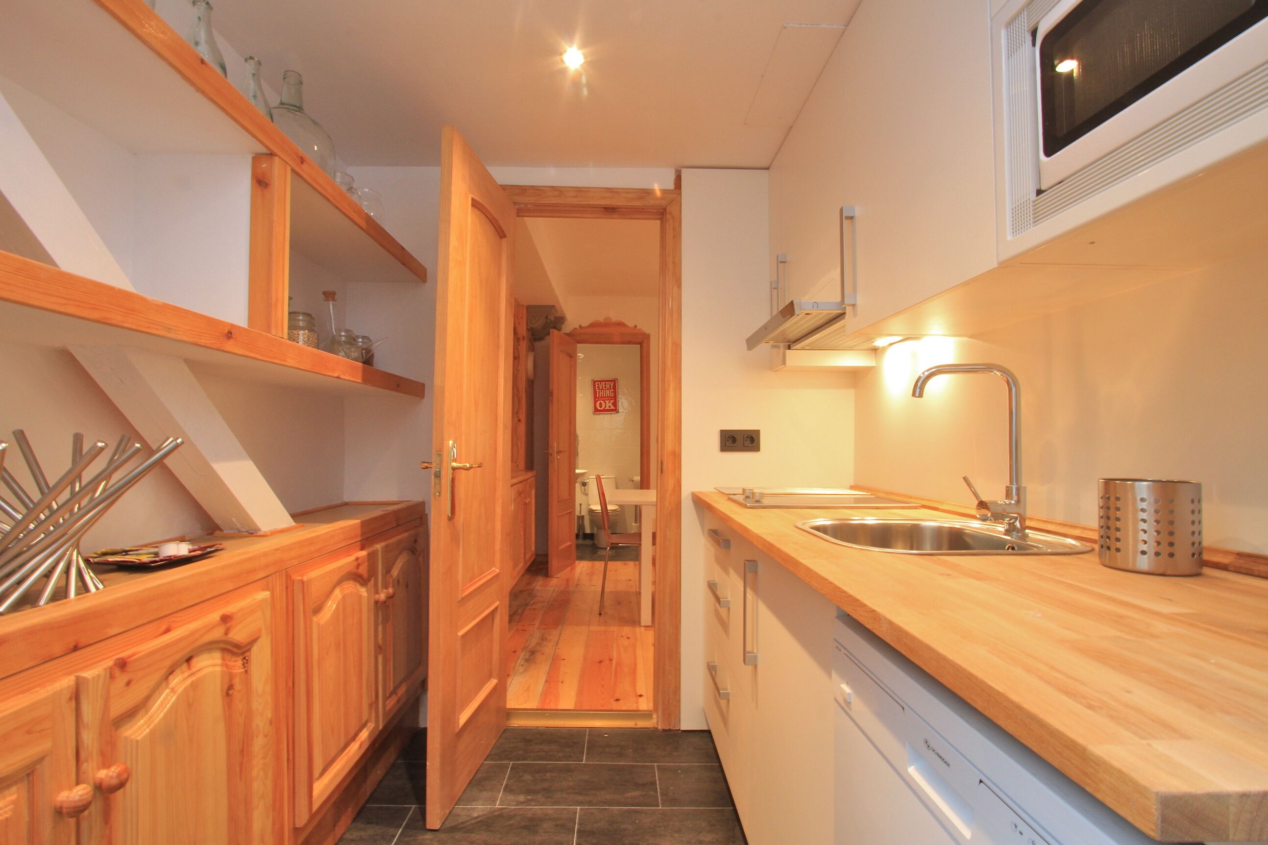 A compact kitchen with wooden cabinets, a stainless steel sink, and a microwave.