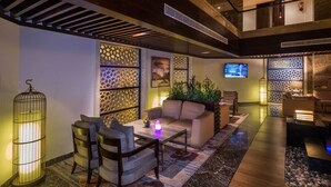 A modern lobby with a seating area, a TV screen, and decorative lighting. - Boudl AL Tahlia (Jeddah)