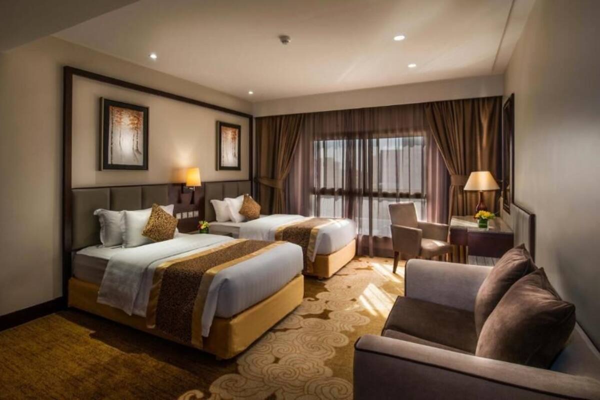 A hotel room with two beds, a sofa, a desk, and a chair.
