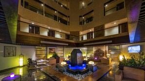 A spacious lobby with a central water feature, multiple seating areas, and a television screen on the wall. - Boudl AL Tahlia (Jeddah)
