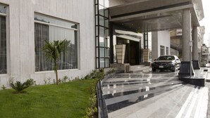 A modern building with a large glass entrance, a car parked in front, and a well-maintained lawn. - Boudl AL Tahlia (Jeddah)