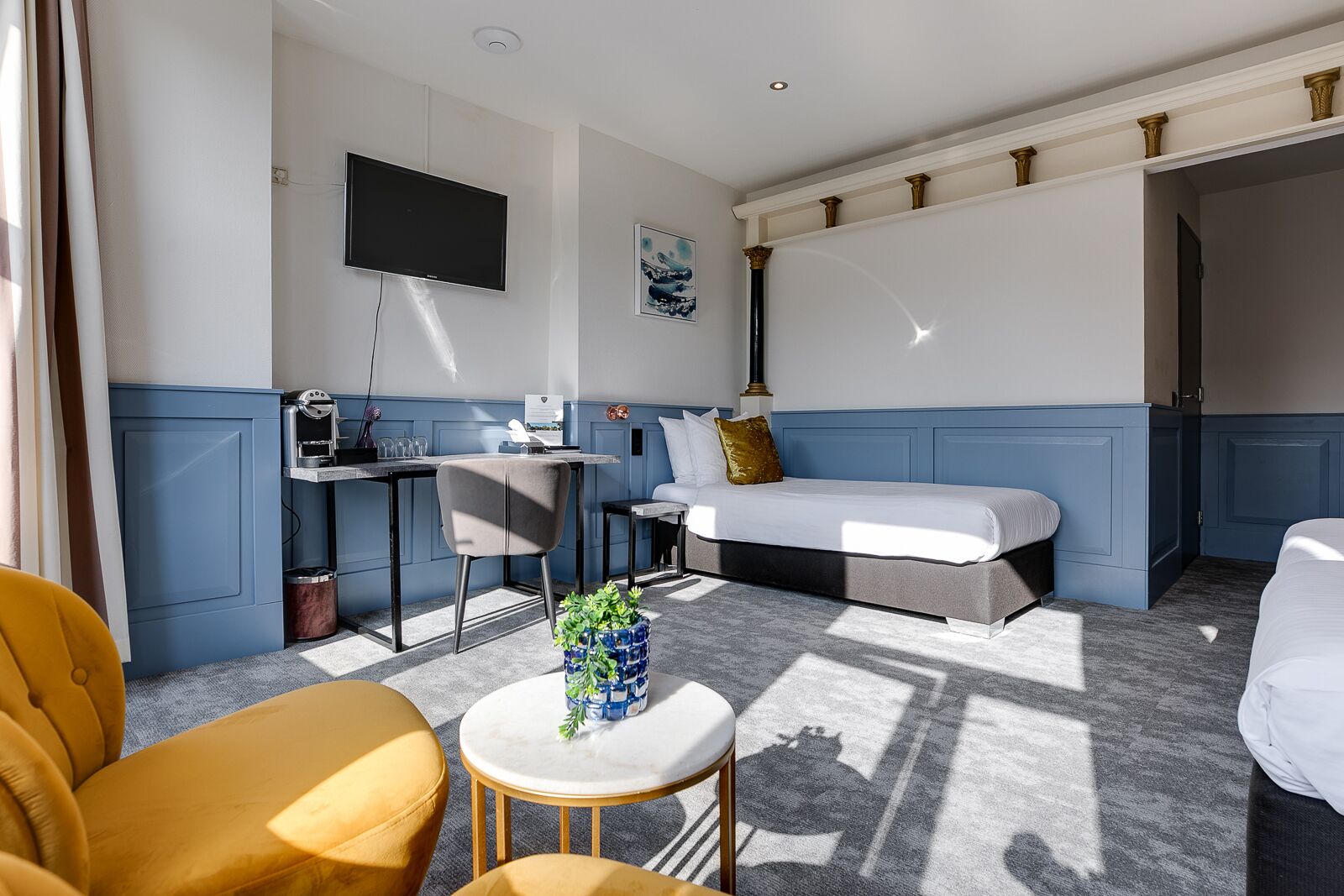 Une chambre d’hôtel avec un lit, un bureau doté d’une machine à café, une télévision et une fenêtre avec des rideaux.