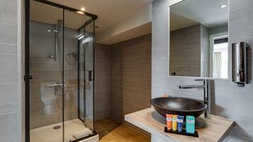 A modern bathroom with a glass-enclosed shower, a large mirror, and a wooden vanity with a bowl sink.