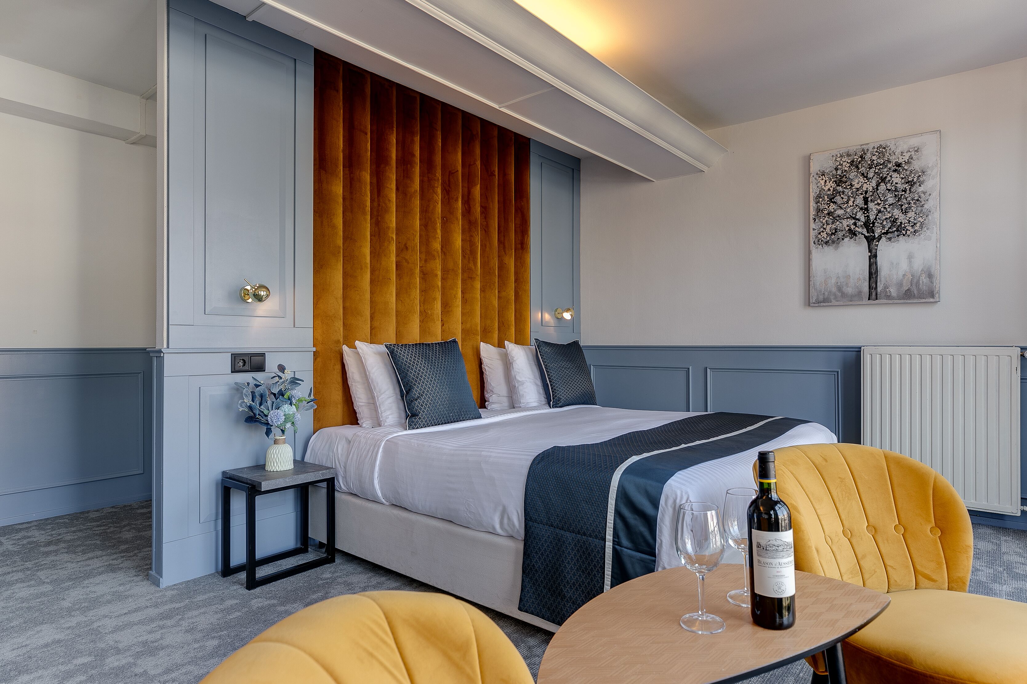 Ein Hotelzimmer mit einem Bett, einem Nachttisch und einem kleinen Tisch mit einer Flasche und Gläsern.