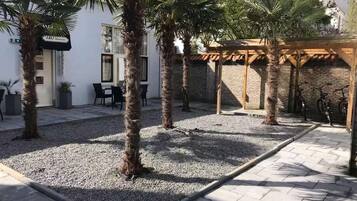 Un cortile con palme, un'area salotto coperta e biciclette.