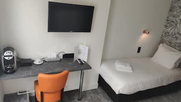 A hotel room with a bed, a desk with a chair, a television, and a coffee maker.