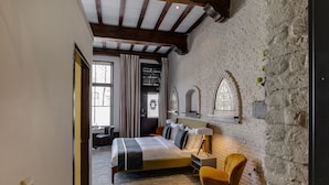 A bedroom with a bed, a chair, a desk, and a window with curtains. - Hotel Royal Bridges (Delft)