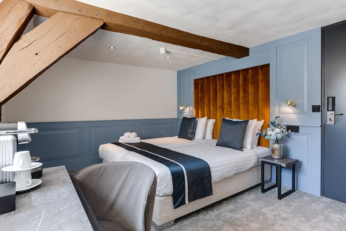A modern hotel room with a large bed, a small side table, and a marble-topped desk.