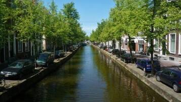 Ein Kanal, gesäumt von parkenden Autos und Bäumen, mit Gebäuden an beiden Seiten.