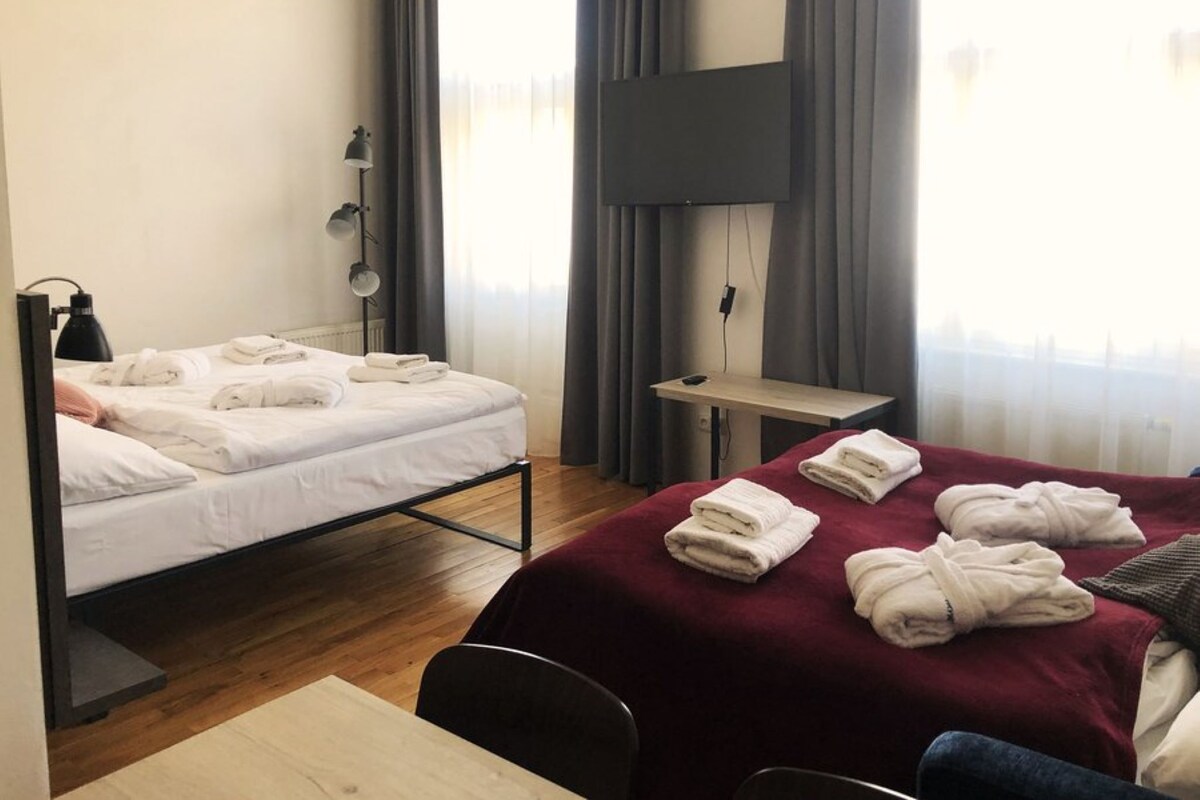 A hotel room with a bed, a desk, a chair, and a TV.