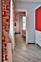 Un dormitorio moderno con cama, un armario rojo y suelo de madera.