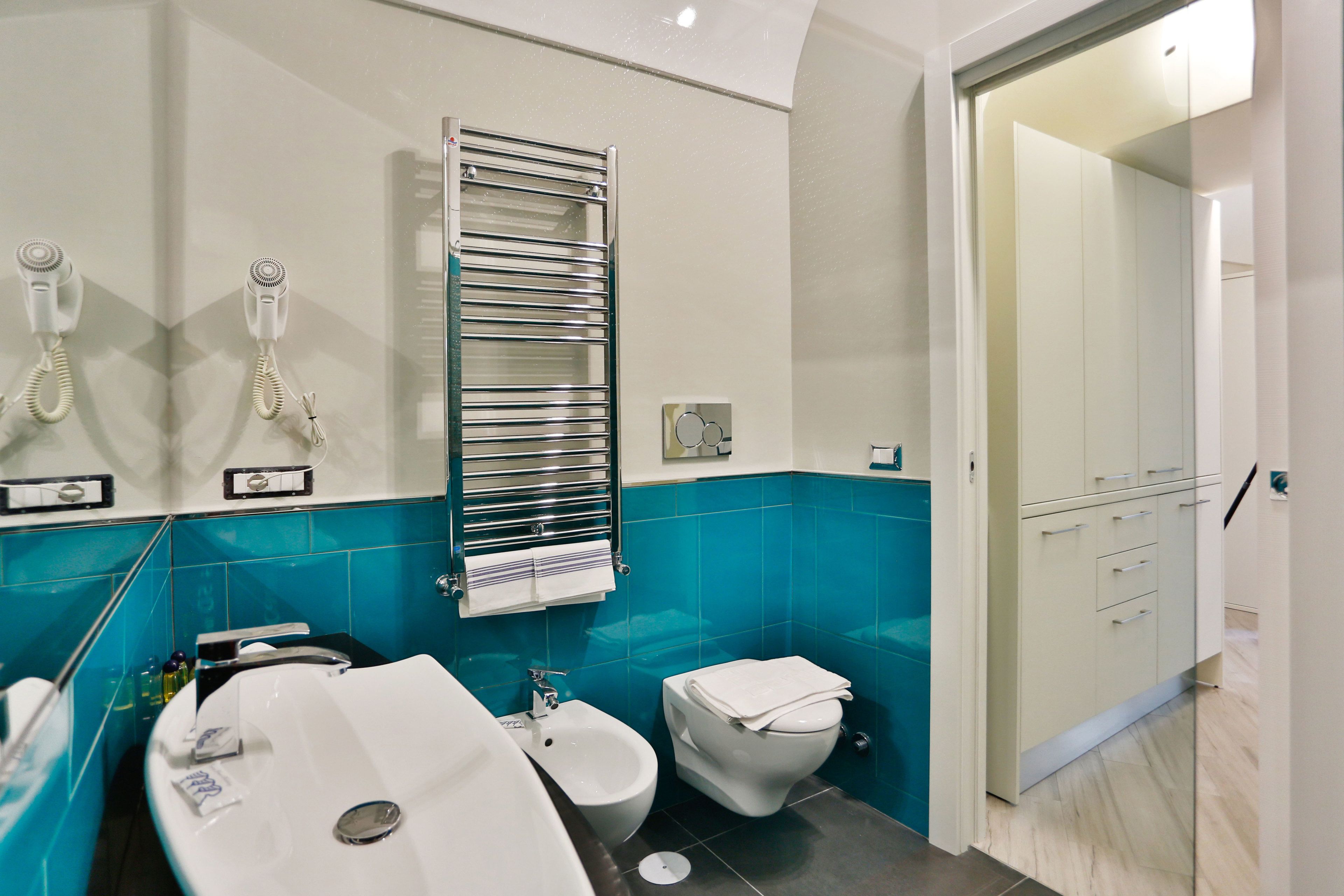 Un baño moderno con un lavamanos grande, un bidé y un perchero para toallas.