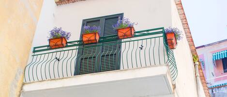 A multi-story building with balconies, each with metal railings and potted plants.