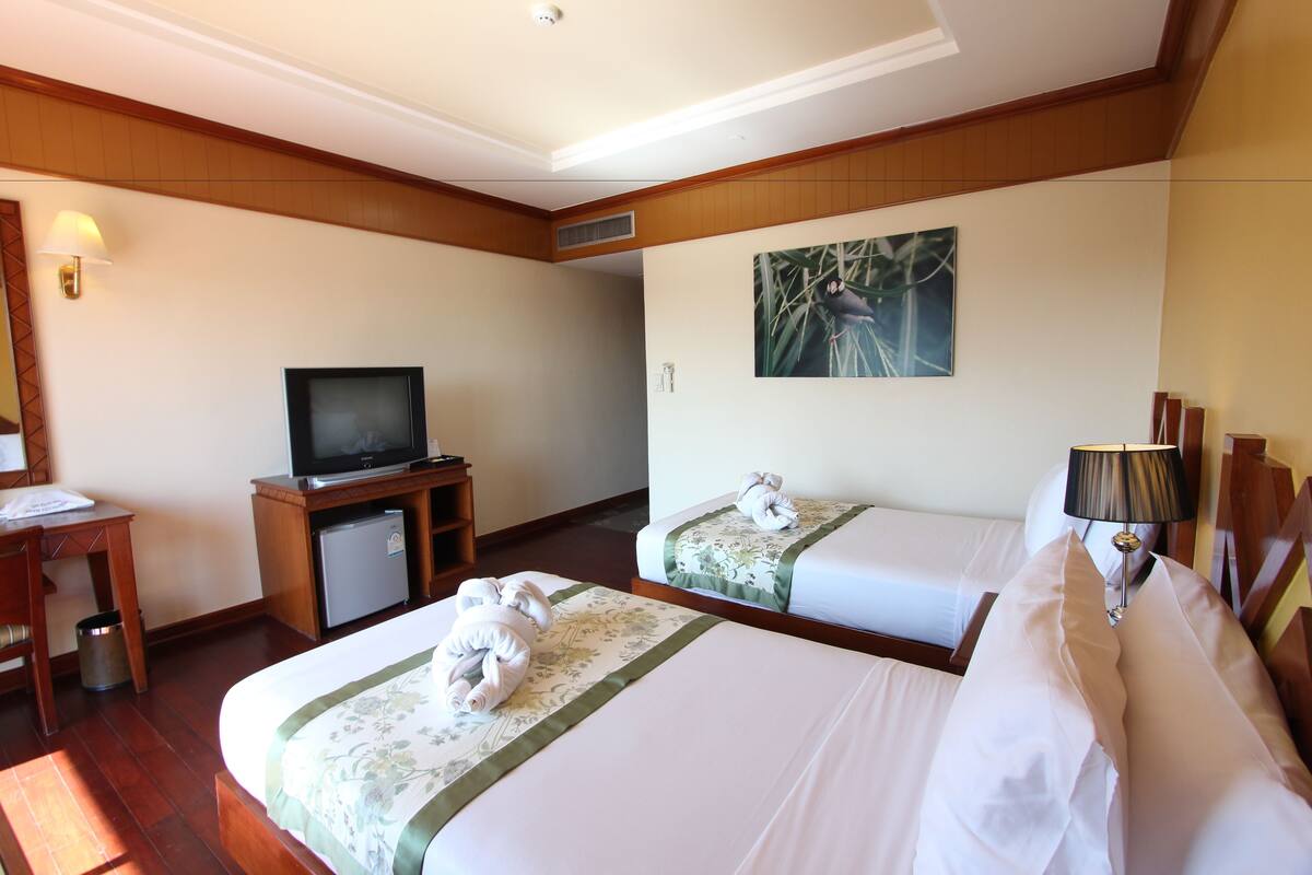 A hotel room with two beds, a television, a desk, and a lamp.