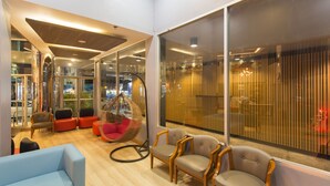 Un intérieur moderne avec un coin salon comprenant un canapé bleu, des chaises en bois et un fauteuil suspendu.