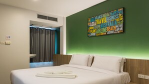 Une chambre d’hôtel moderne avec un lit soigneusement fait, une œuvre d’art murale sur le thème du voyage et une salle de bain avec un rideau.