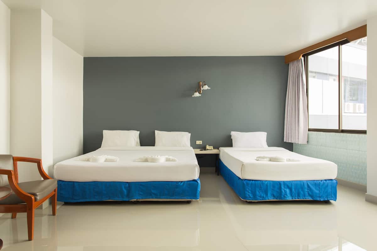 A hotel room with two beds, a desk, a chair, and a window.