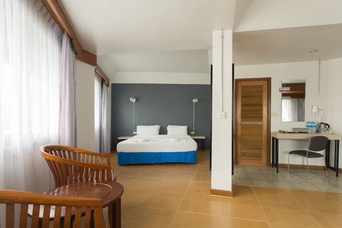 A hotel room with a bed, a desk, a chair, and a bathroom door.