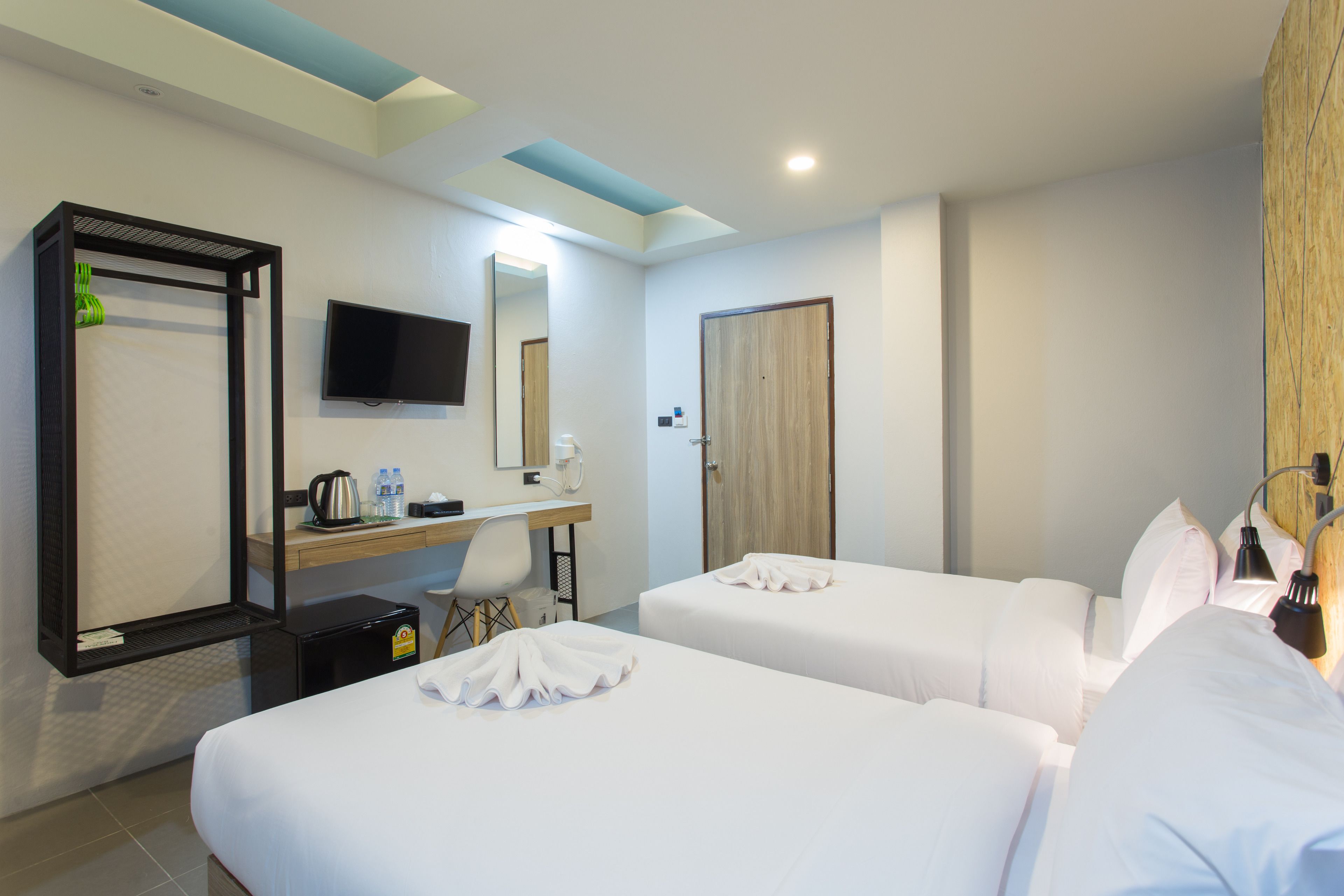 A hotel room with two beds, a desk with a chair, a television, and a mirror.