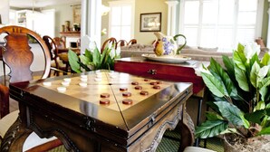 A checkered game board on a wooden table in a room with a dining area, a sofa, and potted plants. - Desoto Beach Bed & Breakfast (Tybee Island)