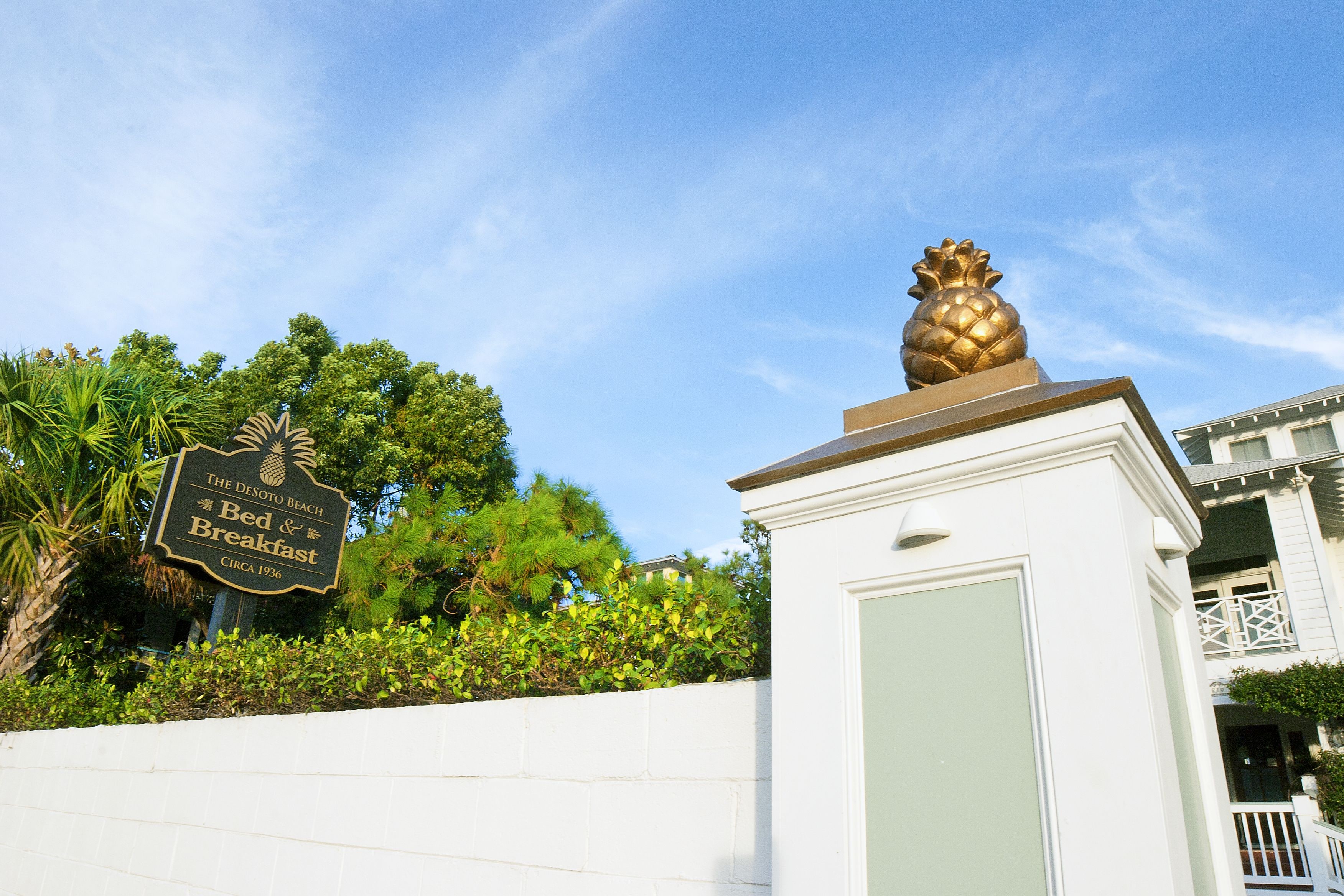 A sign for 'The Desoto Beach Bed & Breakfast' with a pineapple statue on top.