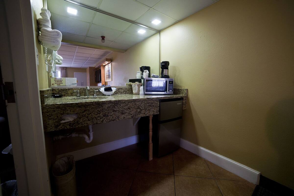 A compact kitchen with a granite countertop, a microwave, a coffee maker, and a sink.
