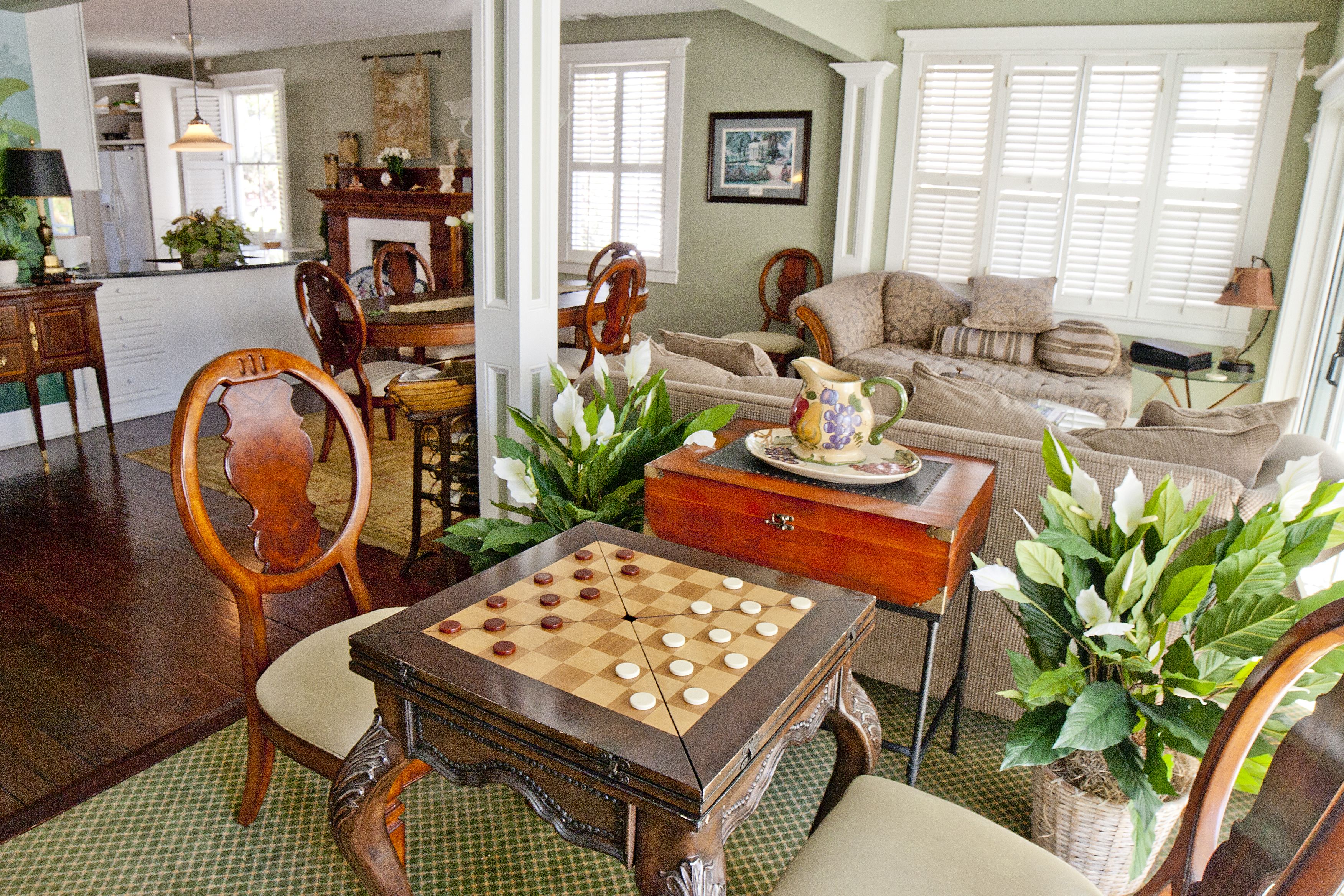A cozy living room with a chessboard, comfortable seating, and a dining area with a table and chairs.