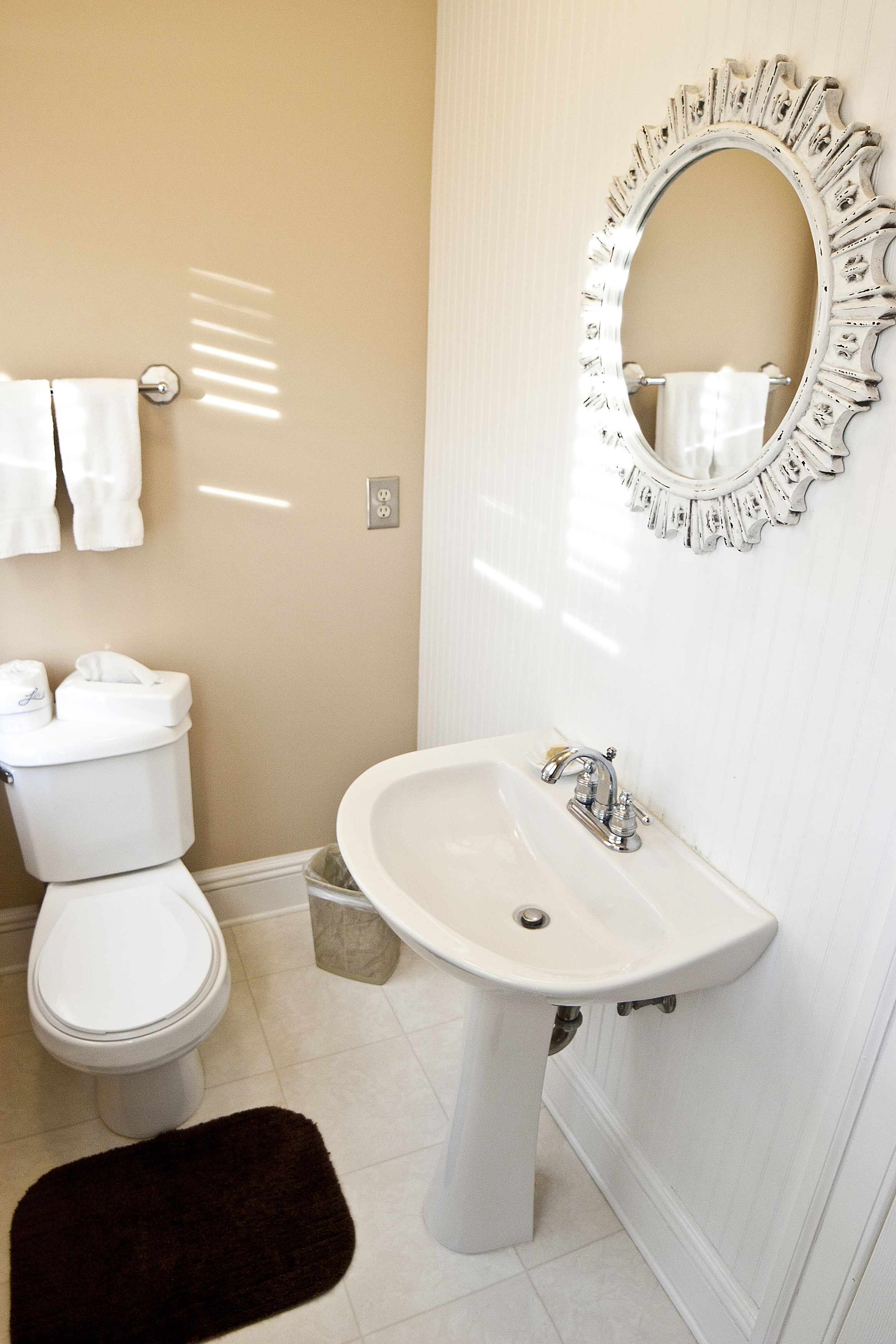 A bathroom with a toilet, sink, and a decorative mirror.