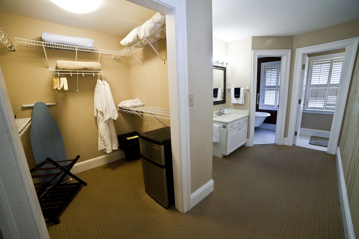 A compact bathroom with a shower, a sink, and a small storage area.