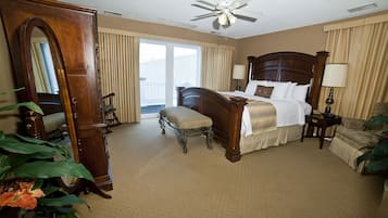A hotel room with a large bed, a sitting area, a dresser, and a ceiling fan.
