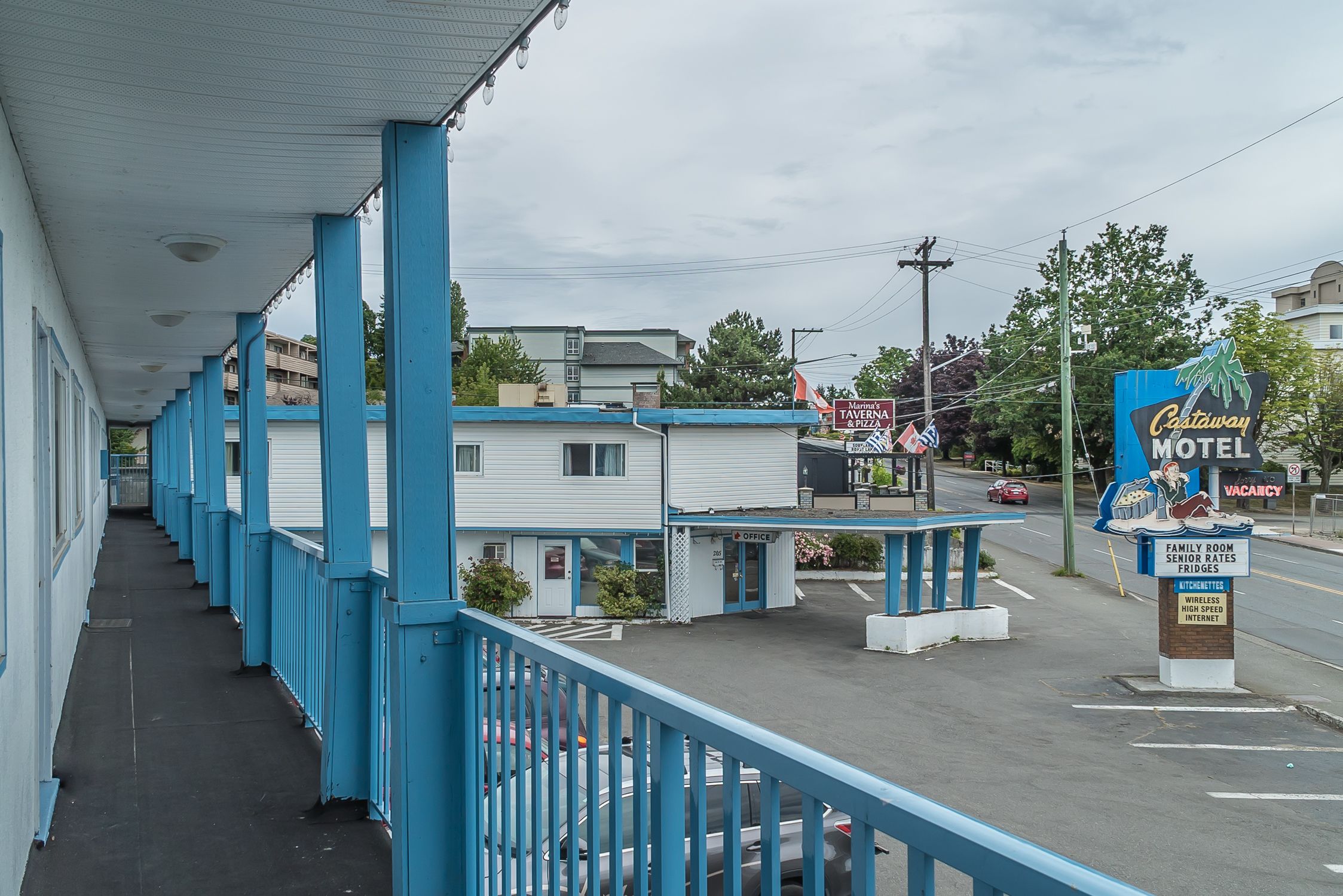A motel with a covered walkway, a sign for 'Castaway Motel' with amenities like senior rates and high-speed internet, and a visible 'Tavern & Pizza' sign.