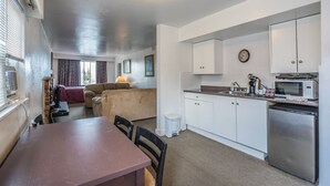 Un espace de vie compact comprenant un coin repas, une kitchenette et un coin salon confortable.