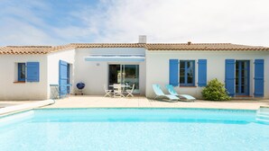 A swimming pool with a patio area, including lounge chairs and a table. - Madame Vacances Le Domaine de Vertmarines (Saint-Jean-de-Monts)