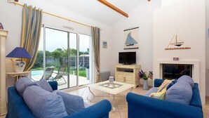 A living room with a sofa, TV, and a fireplace. - Madame Vacances Le Domaine de Vertmarines (Saint-Jean-de-Monts)