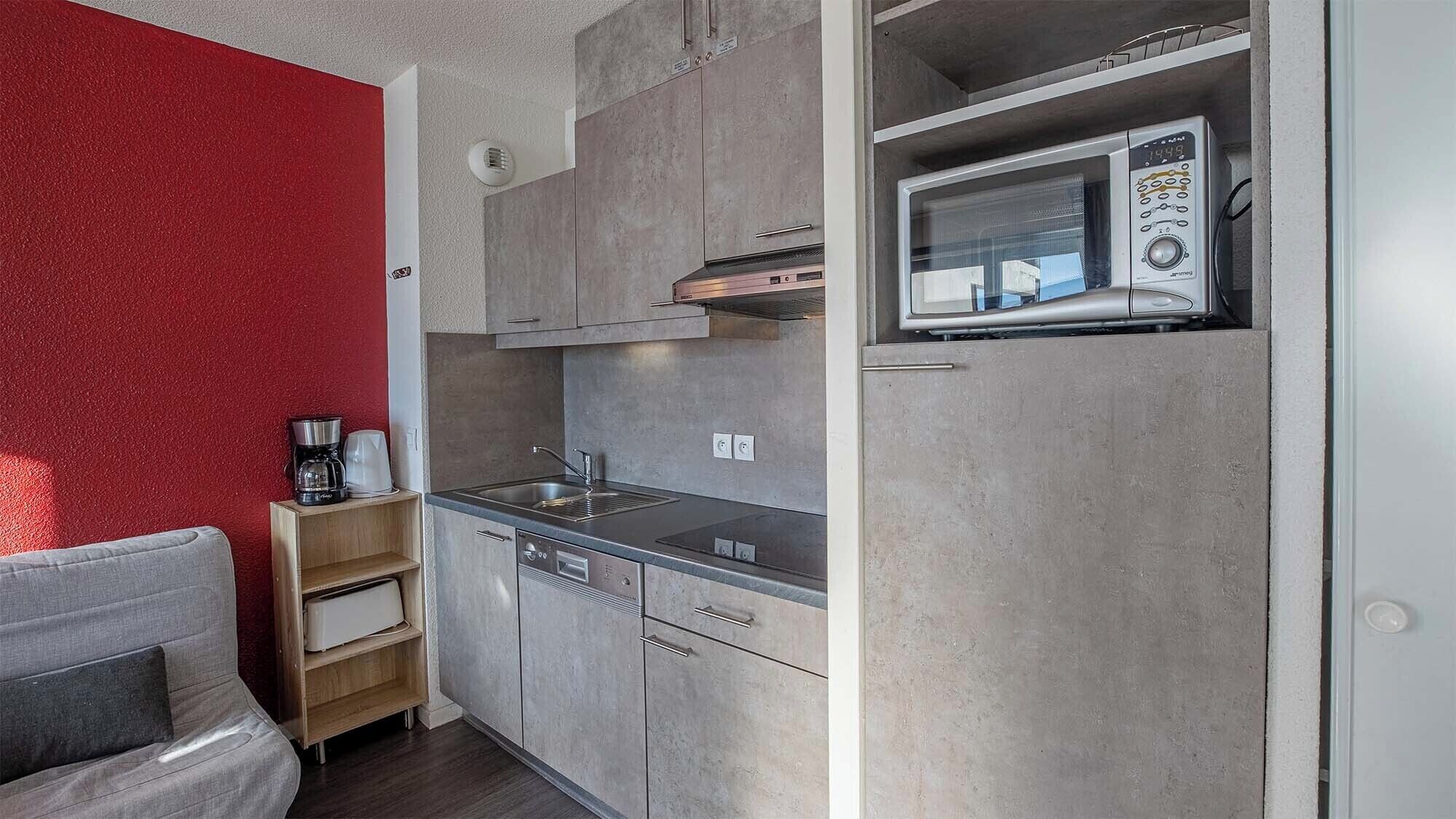 A compact kitchen with a microwave, sink, and wooden cabinets.