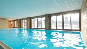 Ein Hallenbad mit großen Fenstern und Blick ins Freie.