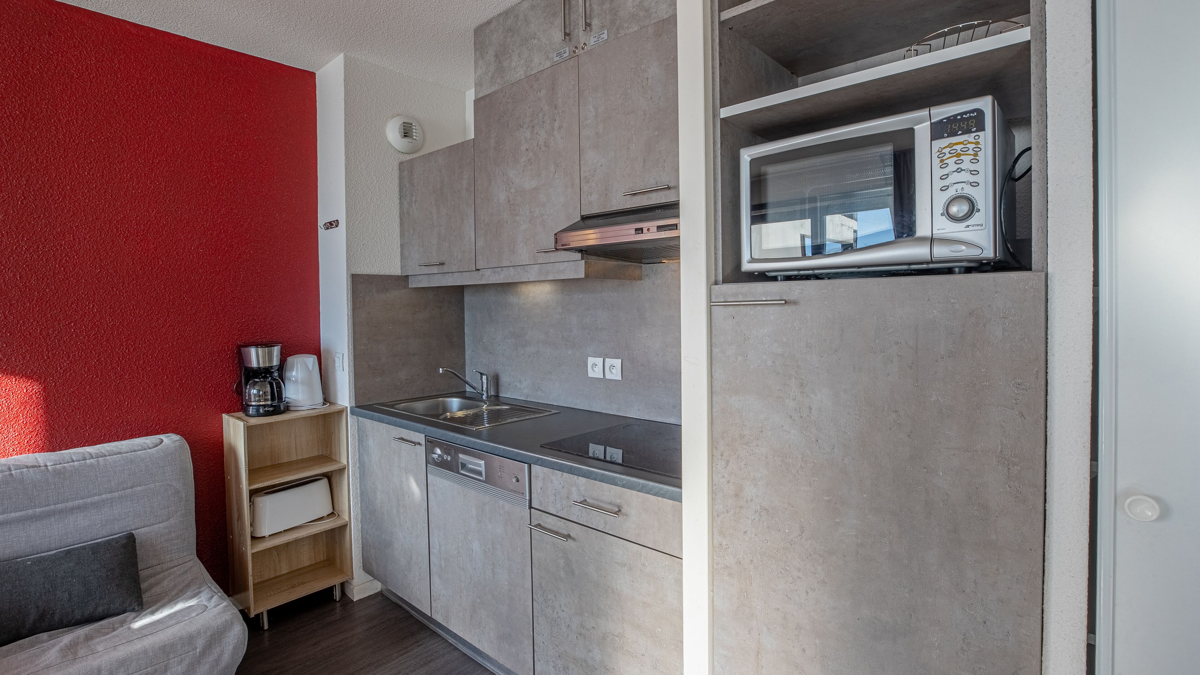 A compact kitchenette with a microwave, sink, and built-in oven.